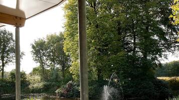 Un espacio al aire libre con mesas y sillas, un estanque y una fuente.