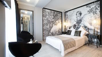 A bedroom with a large bed, a chair, a nightstand, and a wall with a detailed mural.