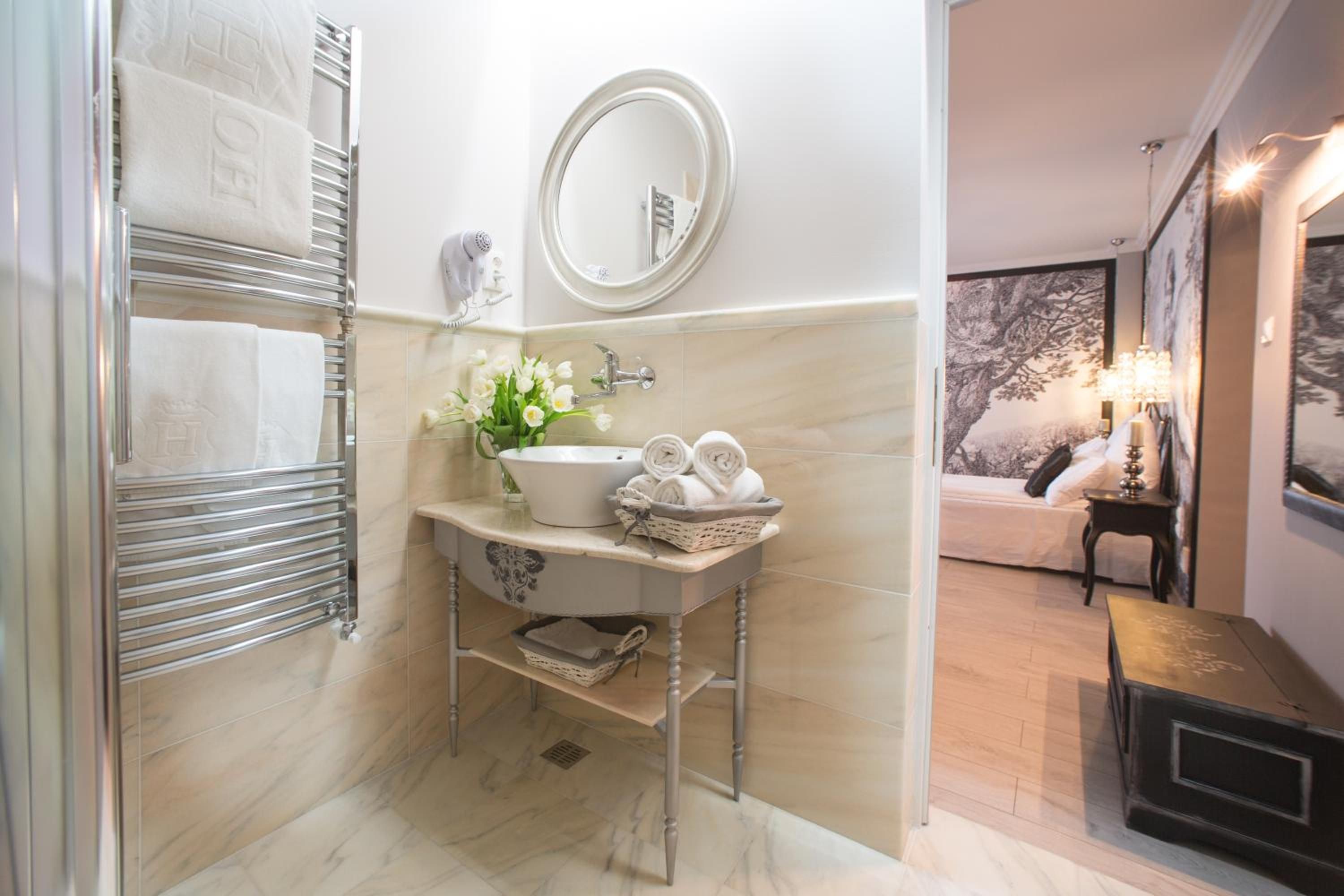 A bathroom with a marble floor, a sink with a vase of flowers, a towel rack, and a mirror.