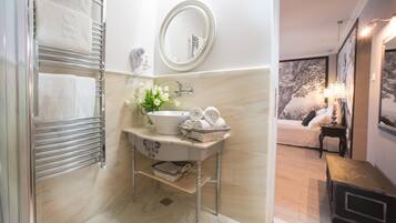 A bathroom with a marble floor, a sink with a vase of flowers, a towel rack, and a mirror.