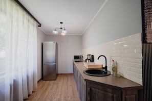 A compact kitchen with a refrigerator, microwave, and sink.