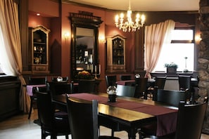 A dining room with a chandelier, wooden furniture, and a large mirror.