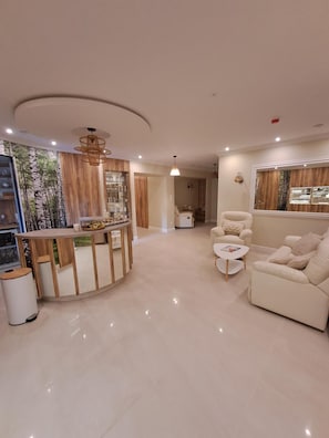 A modern living room with a sofa, a coffee table, and a dining area with a wooden table and chairs.