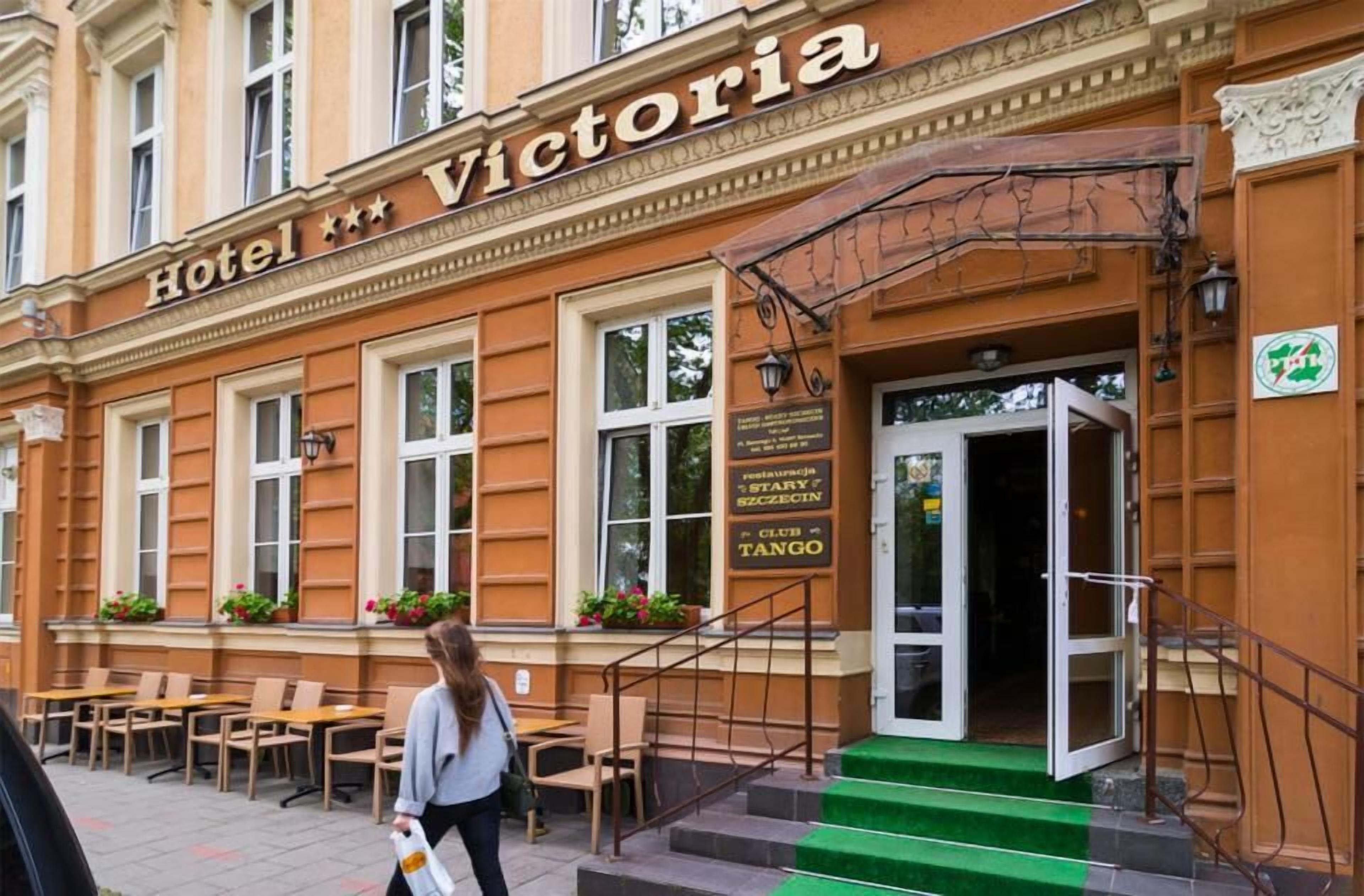 Ein Gebäude mit einem Schild, auf dem 'Hotel Victoria' steht, und einer Treppe, die zum Eingang führt.