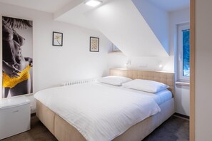 Un dormitorio con cama, mesita de noche, radiador y ventana con vistas.
