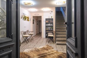 Un pasillo con suelo estampado, un comedor con mesa y sillas, una escalera y un estante con adornos.