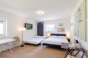 Un dormitorio con dos camas individuales, un escritorio, una silla, un televisor y obras de arte en las paredes.