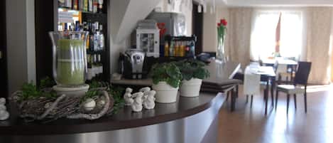 A bar area with a drink dispenser, a coffee machine, and a potted plant.