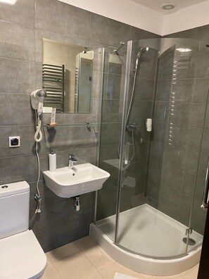Casa de banho moderna com cabine de chuveiro em vidro, lavatório branco e sanita.