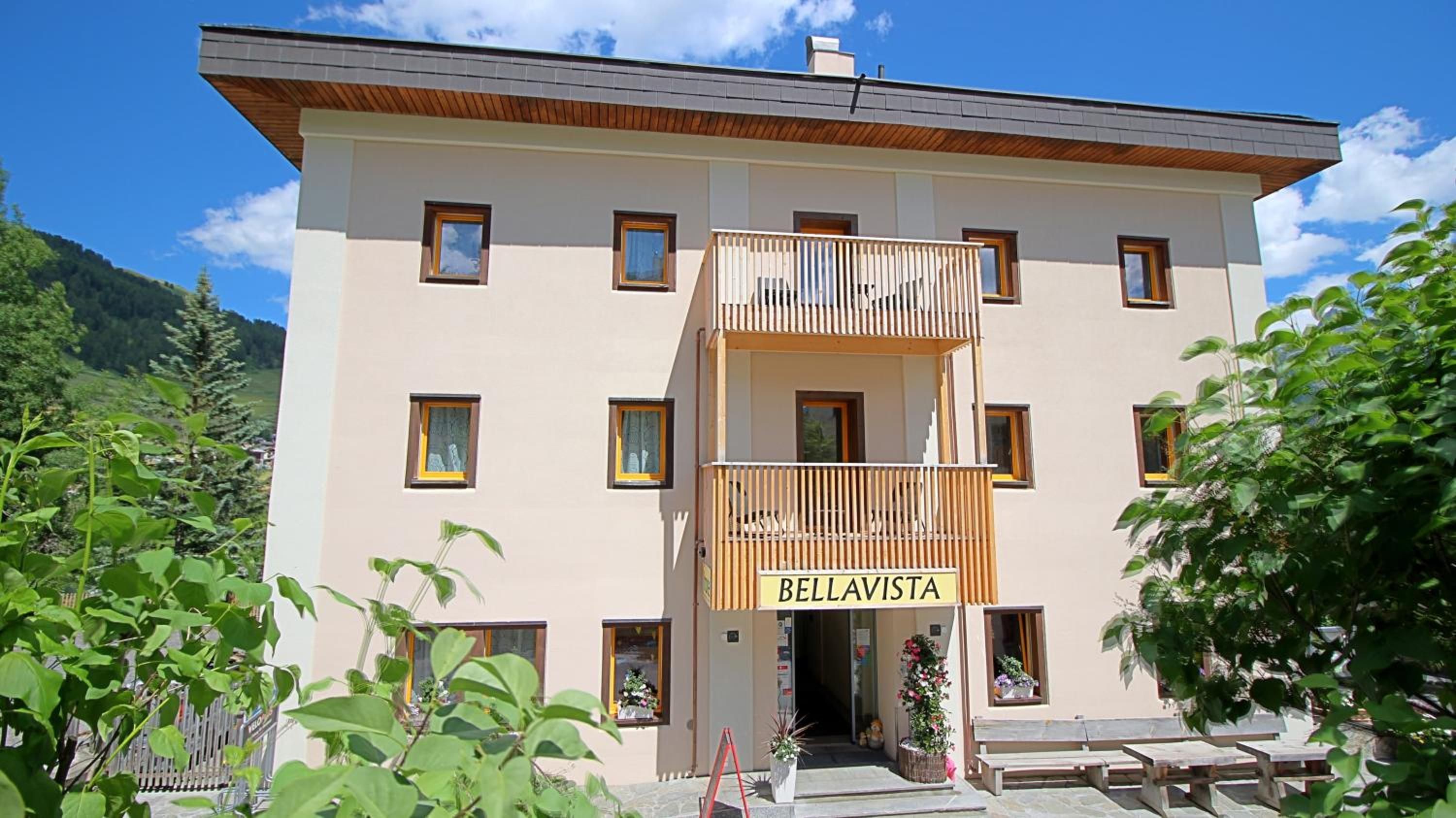 A two-story building with a balcony, a sign reading 'BELLAVISTA,' and a mountainous backdrop.