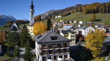A town with a prominent church tower, residential buildings, and a mountainous backdrop.
