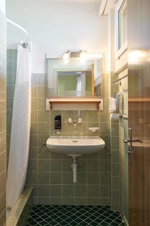 A bathroom with a shower, a sink, and a mirror. - Hotel Bellavista Ftan (Scuol)