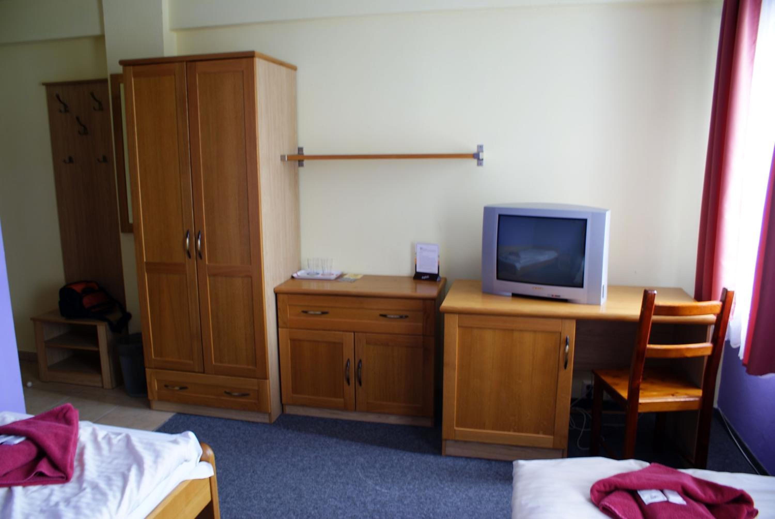 Ein Hotelzimmer mit einem Bett, einem Schreibtisch mit Fernseher, einem Kleiderschrank und einem Sessel.