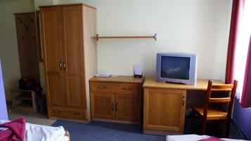 Ein Hotelzimmer mit einem Bett, einem Schreibtisch mit Fernseher, einem Kleiderschrank und einem Sessel.