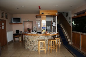 Un vestíbulo con mostrador de piedra, taburetes de bar, un televisor y una escalera.