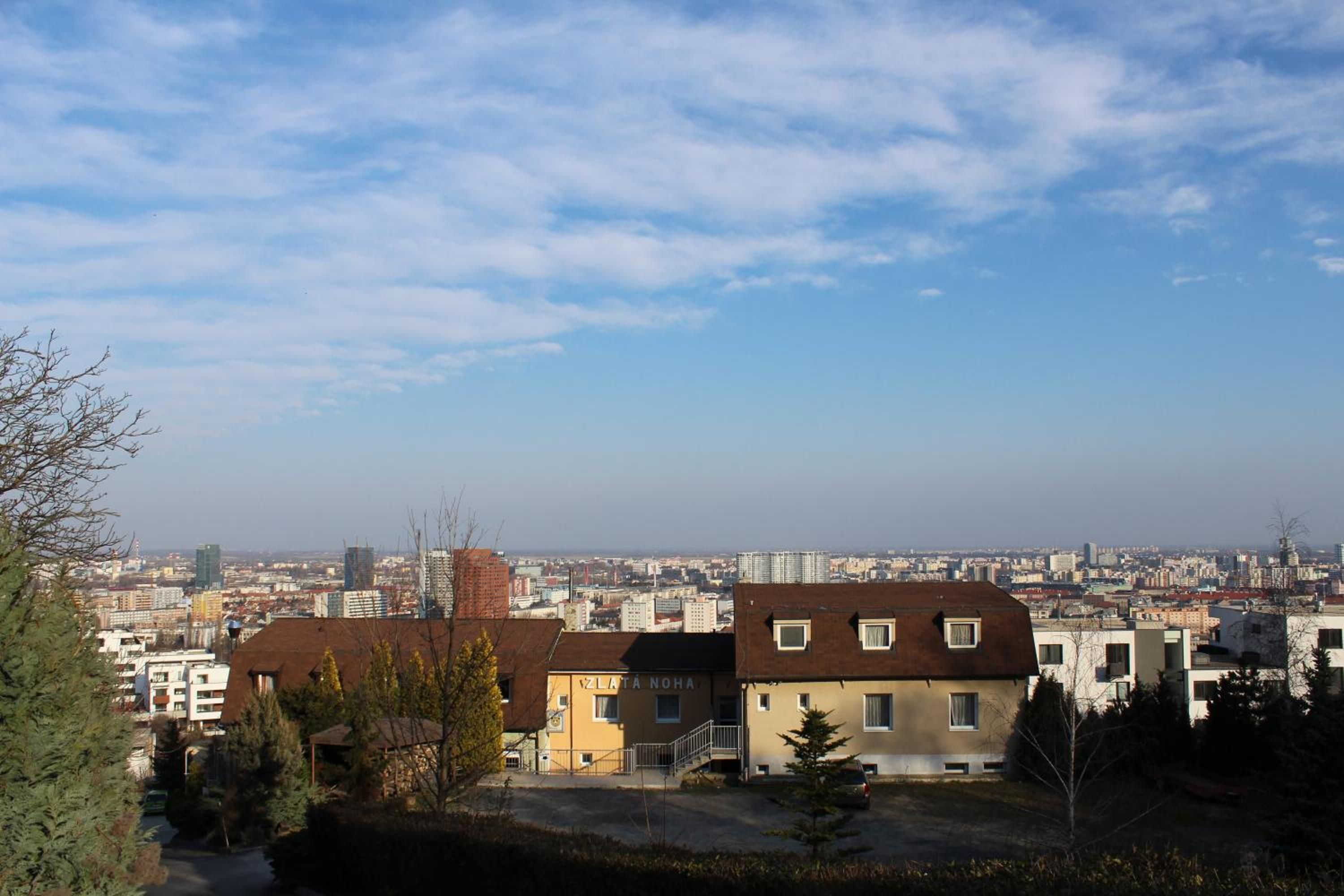 Una zona residencial con una mezcla de edificios modernos y antiguos, cielo despejado y un paisaje urbano lejano.