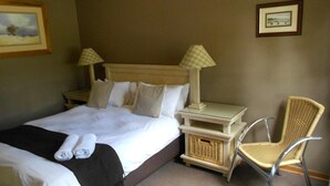 Una habitación de hotel con una cama, dos mesitas de noche, una silla y dos lámparas.