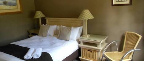 A hotel room with a bed, two bedside tables, a chair, and two lamps.