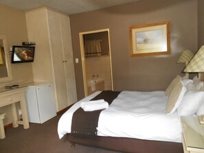 Habitación de hotel con cama, escritorio, televisor, baño y un cuadro en la pared.