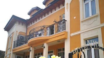 A multi-story building with balconies, a gated entrance, and a flower arrangement.
