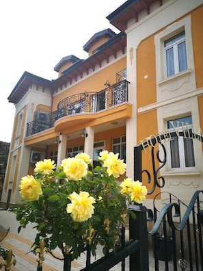 A multi-story building with balconies, a gated entrance, and a flower arrangement. - Villa Paris (Hisarja)