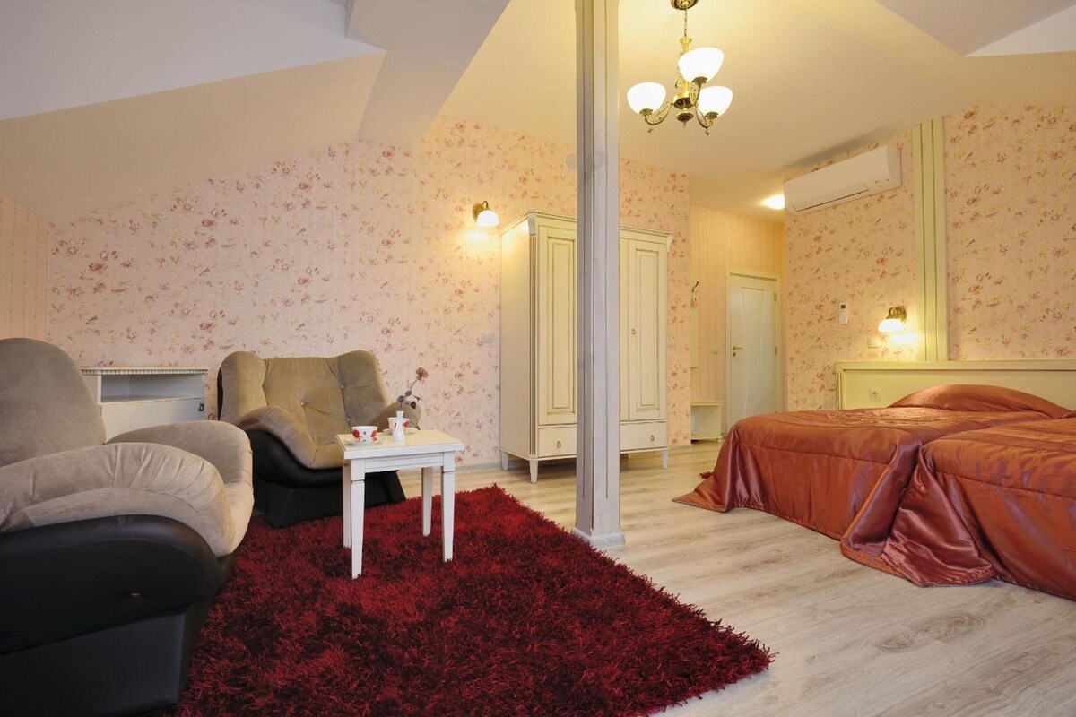 Un dormitorio con una cama, dos sillas, una mesita y un tapete rojo.