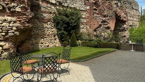 Un patio con pared de piedra, una mesa redonda y sillas.