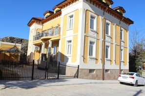 A multi-story building with a yellow facade, a balcony with a wrought iron railing, and a gated entrance. - Villa Paris (Hisarja)