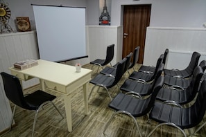 Un salón de conferencias con una pizarra, un reloj y una puerta.