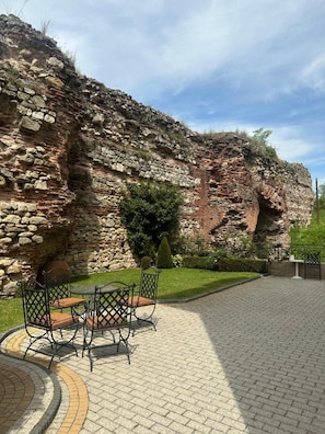Un patio con pared de piedra, una mesa redonda y sillas.