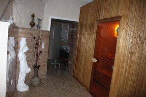 Un pasillo con una puerta de madera, una escultura blanca y un jarrón con ramas.