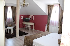 Un dormitorio con una cama, un escritorio, una silla, un televisor y una araña.