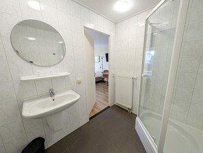 Un baño moderno con cabina de ducha de vidrio, un lavabo con espejo y un inodoro.