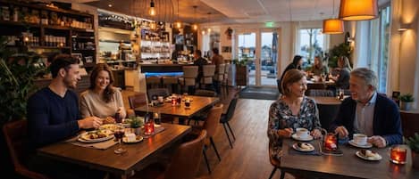 A restaurant interior with wooden tables, chairs, and hanging pendant lights.