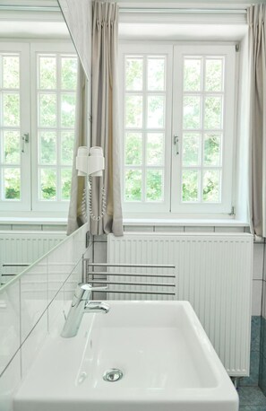 A bathroom with a large window, a white sink, and a towel rack. - De Statie (Brecht)