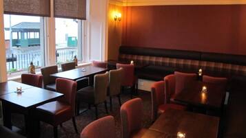 A restaurant with booths and tables, a view of the outside, and a warm interior lighting.