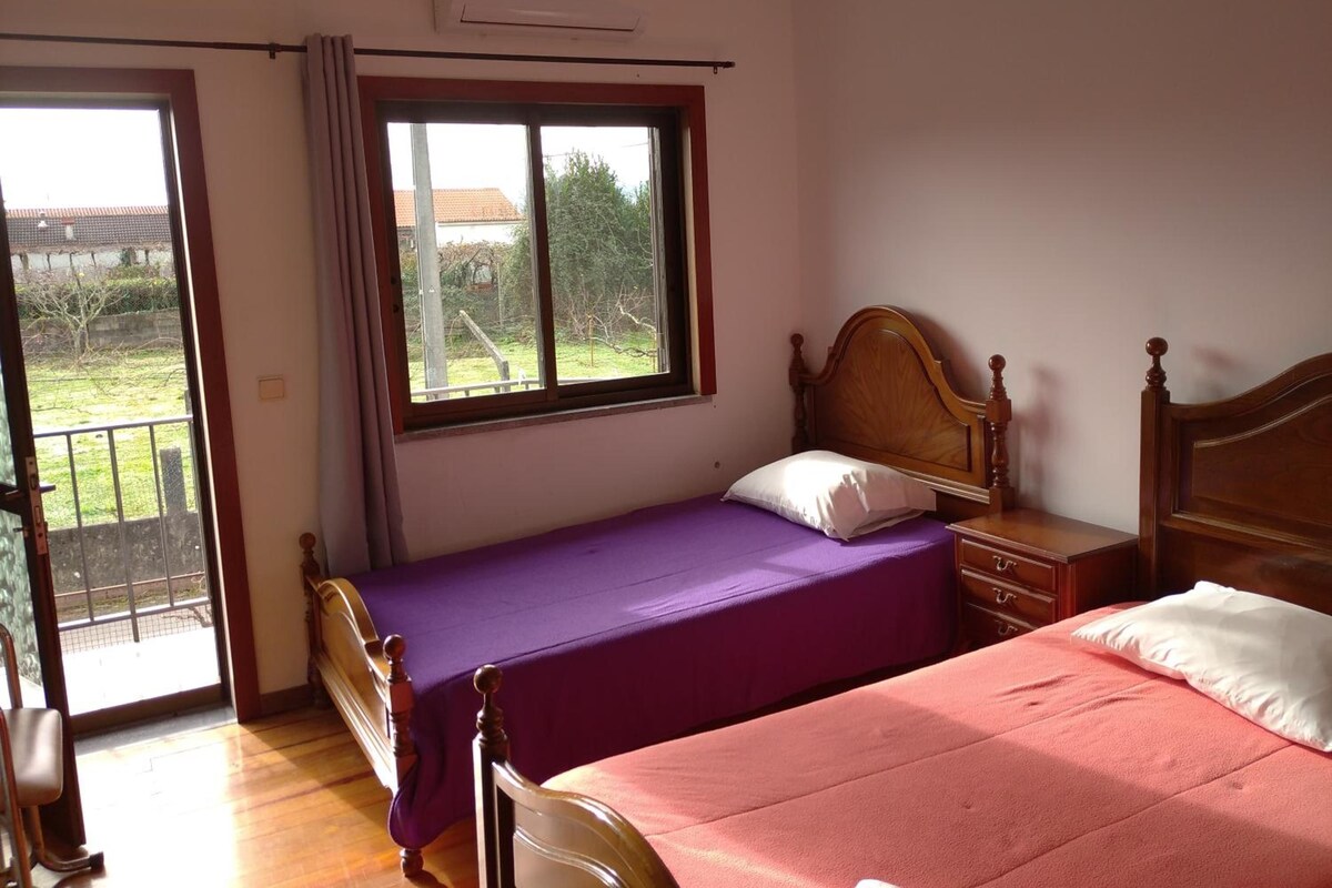 A bedroom with a bed, a nightstand, a window, and a door leading to a balcony.