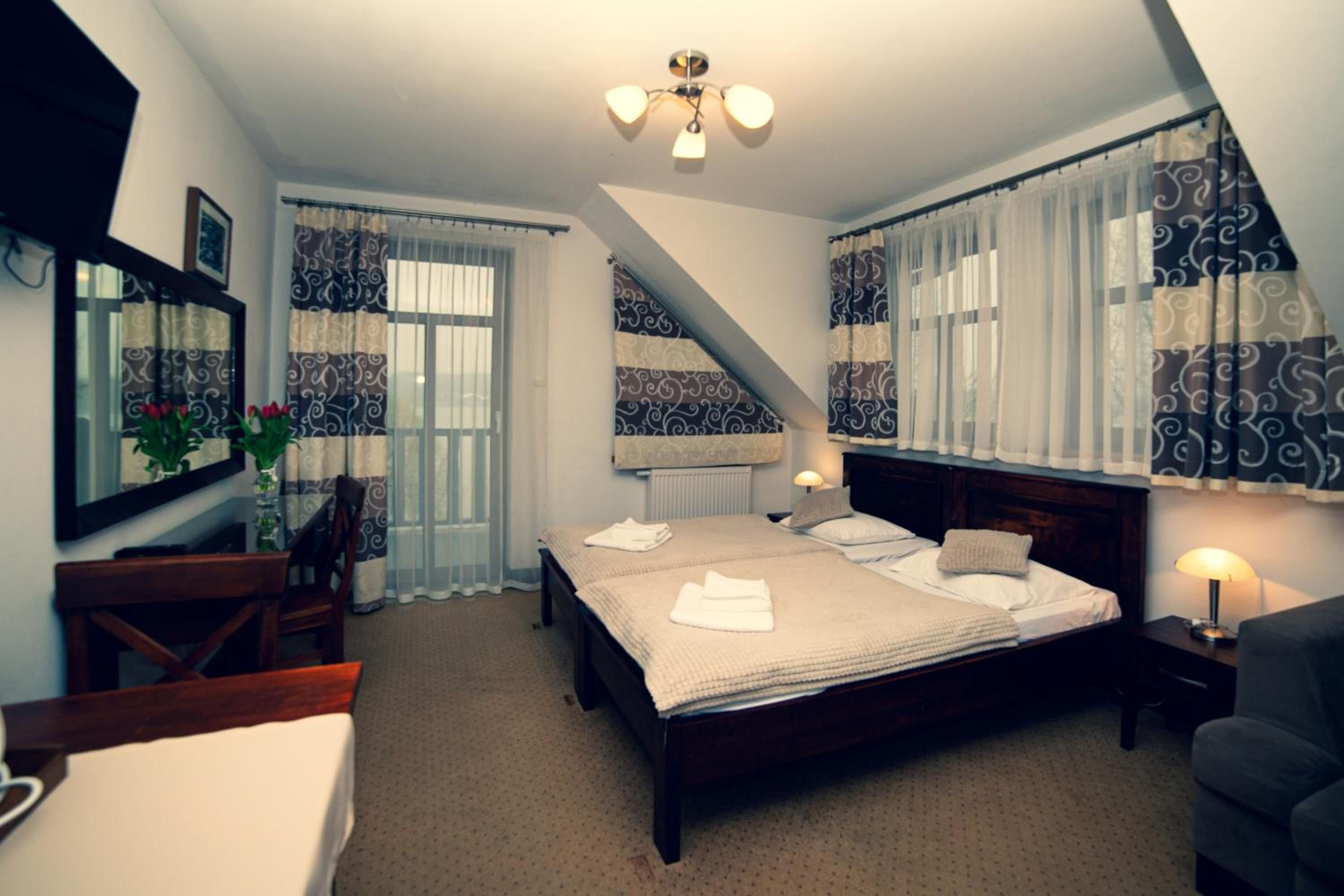 Ein Schlafzimmer mit einem großen Bett, einem Schreibtisch, einem Stuhl, einem Heizkörper und einem Deckenventilator.
