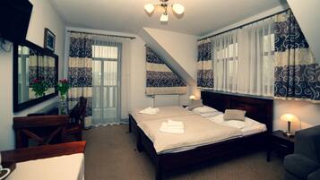 Ein Schlafzimmer mit einem großen Bett, einem Schreibtisch, einem Stuhl, einem Heizkörper und einem Deckenventilator.