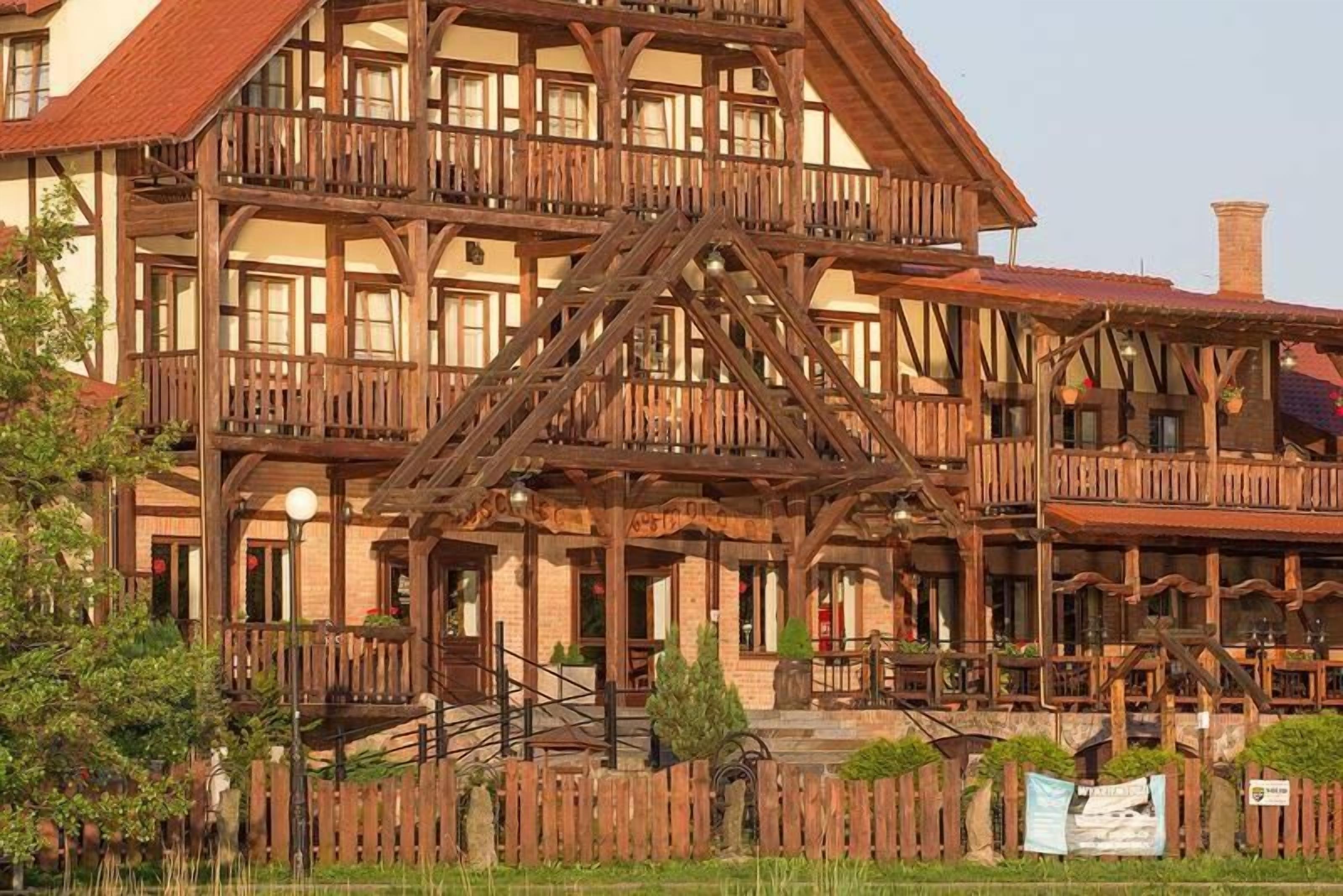 A multi-story building with a wooden facade, balconies, and a staircase leading to the entrance.