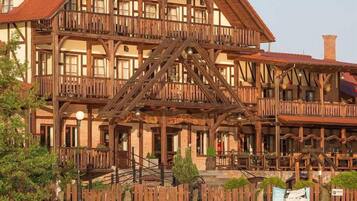 A multi-story building with a wooden facade, balconies, and a staircase leading to the entrance.