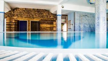 Ein Innenpool mit einer Holzkonstruktion im Hintergrund, einer gefliesten Wand und einer klaren Poolkante.