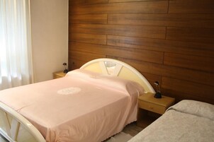 Un dormitorio con cama, mesita de noche, lámpara y cabecero de madera.