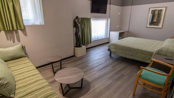 A room with a bed, a chair, a small table, and a window with curtains.