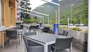 An outdoor seating area with tables and chairs, overlooking a mountainous landscape.