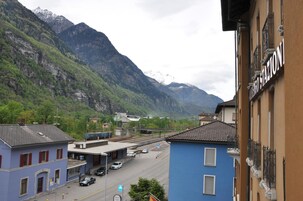 Un pueblo de montaña con una estación de tren, edificios y una carretera con coches.