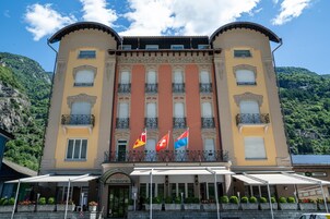 Un hotel con entrada central, varios balcones y banderas.