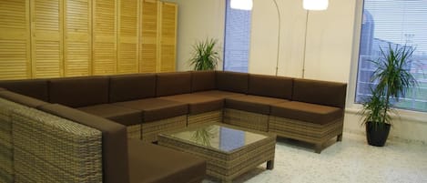 Una sala de estar con un sofá modular, una mesa de centro de vidrio y una planta en maceta.