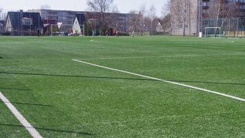 Un terrain de football avec des poteaux de but et un filet, entouré de bâtiments et d’arbres.