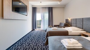 Ein Hotelzimmer mit Bett, Schreibtisch, Stuhl, Wand-Fernseher und Blick ins Freie.